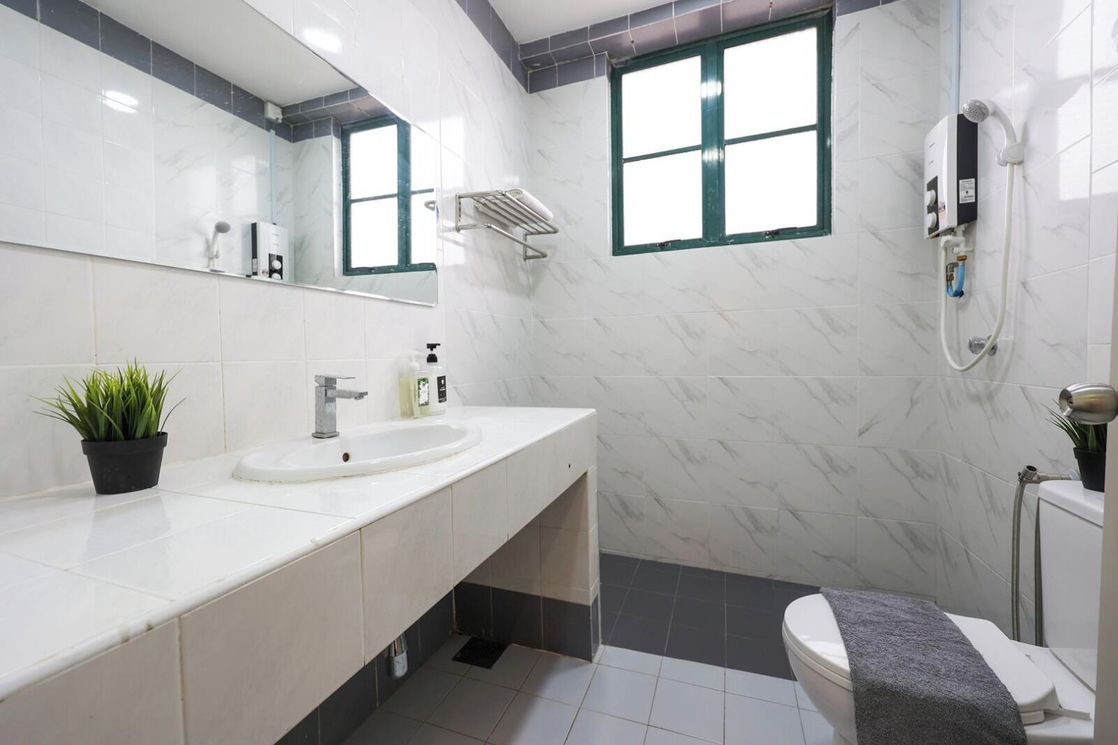 Un baño moderno con lavamanos blanco, espejo y zona de ducha.