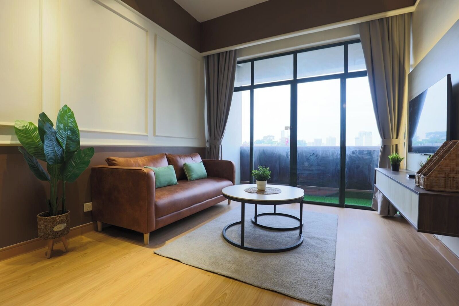 A modern living room with a leather sofa, a round coffee table, and a large window with curtains.