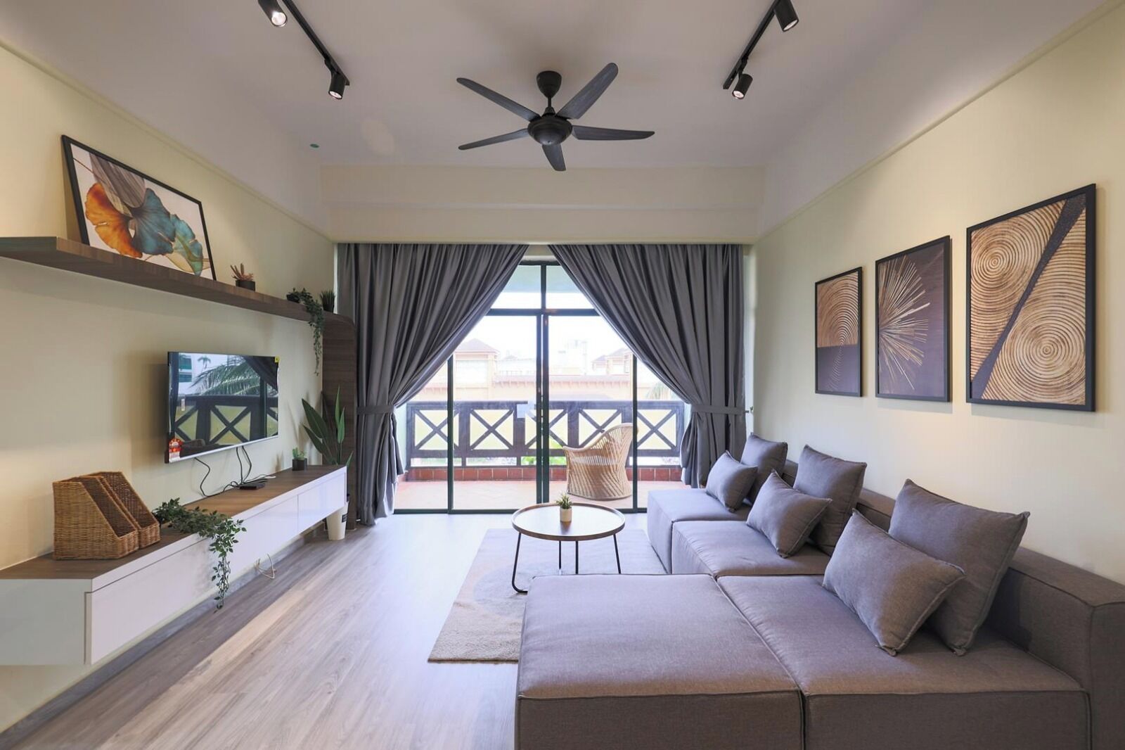 Una sala de estar moderna con sofá, televisor, ventilador de techo y obras de arte en las paredes.