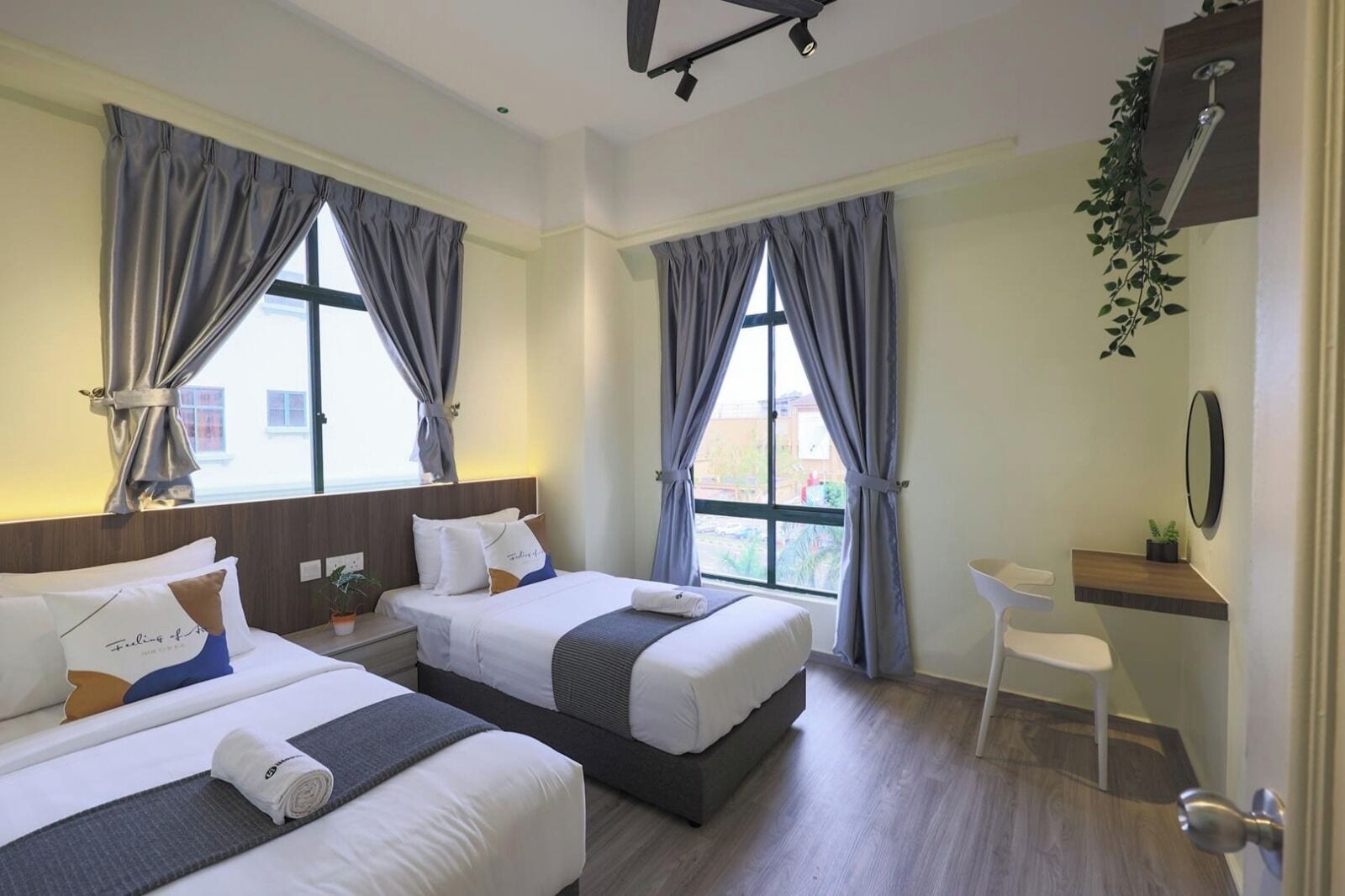 Habitación de hotel con dos camas, un escritorio, una silla y zona de ducha.