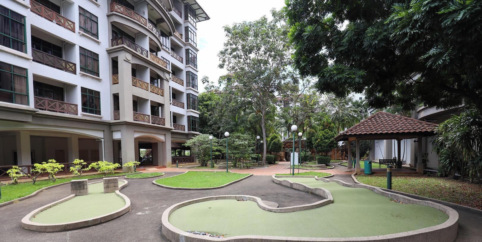 Un patio con piscina, vegetación y un edificio de varios pisos con balcones.