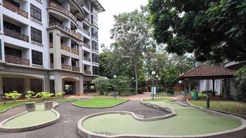 Un patio con piscina, vegetación y un edificio de varios pisos con balcones.