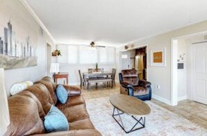 Relax in this inviting living room with a comfortable sofa, dining area, and large window.