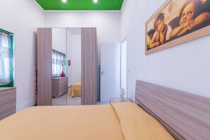 A bedroom with a bed, a wardrobe, a mirror, a painting, and a door leading to another room. - Apartment "Sicania" with Balcony, A/C & Wi-Fi (Noto)