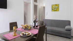 Een eetgedeelte met een tafel gedekt voor twee personen, een bank en een schilderij aan de muur.