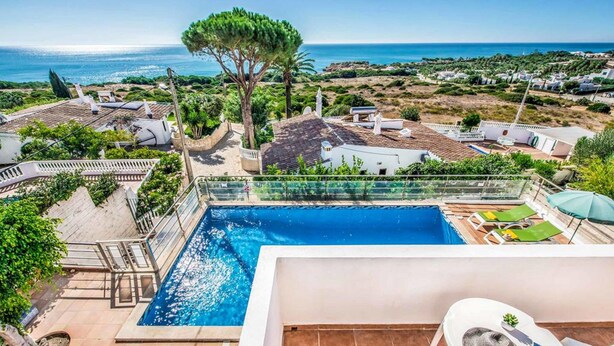 A swimming pool with a view of the sea, a tree, and a white building. - Villa Oceano with Sea View, Pool, Garden & Wi-Fi (São Rafael)