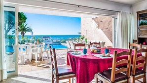 A dining area with a table set for two, overlooking a pool and the sea. - Villa Oceano with Sea View, Pool, Garden & Wi-Fi (São Rafael)