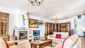A living room with a fireplace, sofa, coffee table, and a television. - Villa Oceano with Sea View, Pool, Garden & Wi-Fi (São Rafael)
