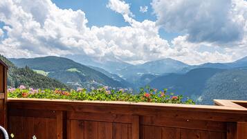 A wooden deck with a view of mountains and a clear sky.