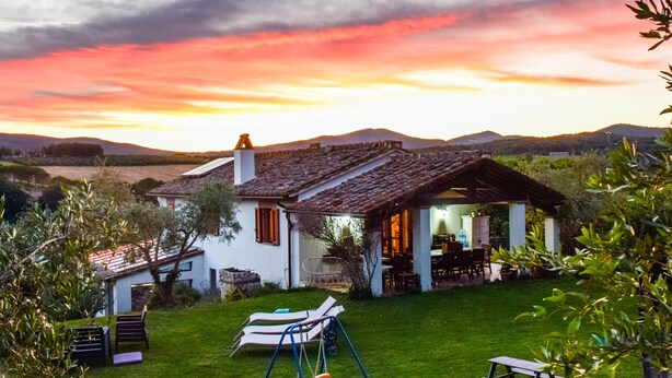 Une maison avec un toit en pente, une terrasse dotée de mobilier d’extérieur et une vue sur le paysage environnant.