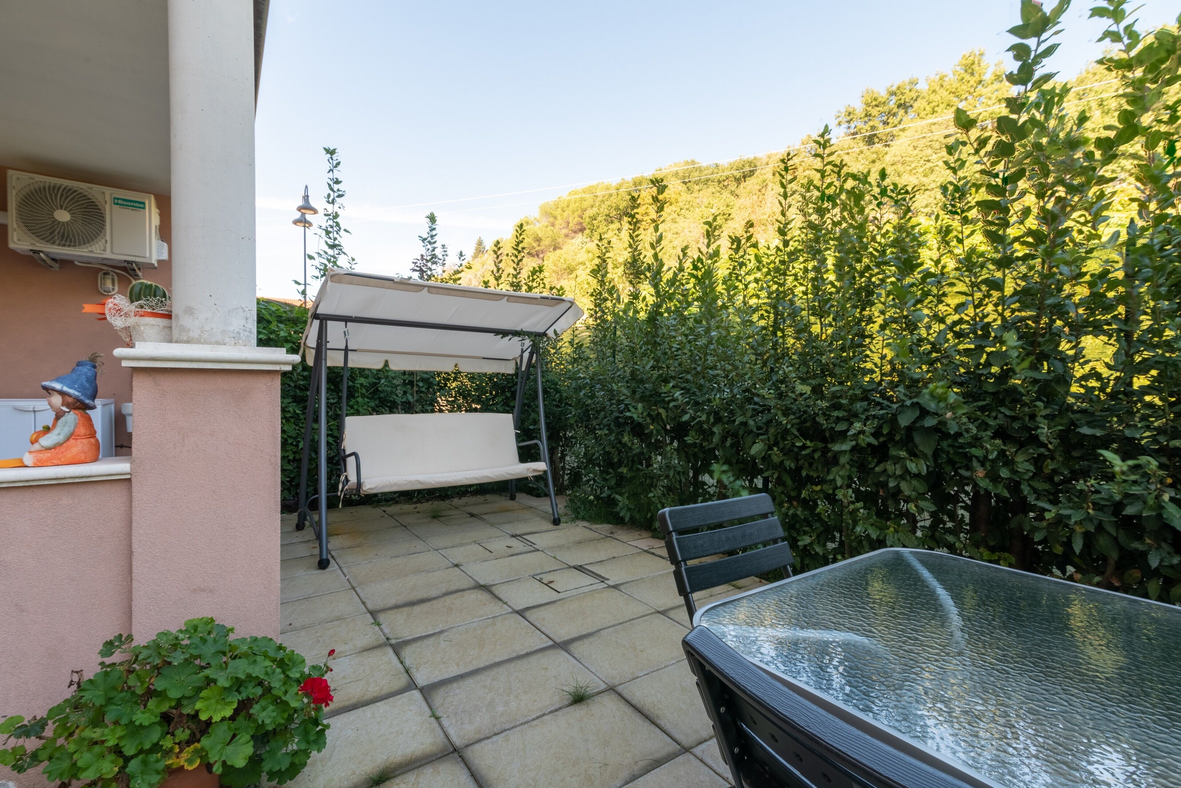 Eine Terrasse mit Tisch und Stühlen, ein überdachter Sitzbereich und ein Blumentopf.
