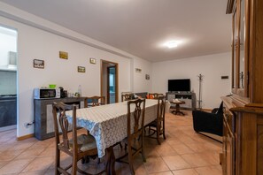 Ein Essbereich mit Tisch und Stühlen, eine Küchenzeile mit Mikrowelle und ein Fernseher.