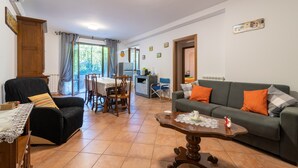 A living room with a sofa, a coffee table, a dining table with chairs, and a kitchen area in the background. - Apartment "Casaentino" with Wi-Fi & Terrace (Capolona)