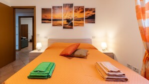 A hotel room with a large bed, two bedside lamps, a wall-mounted artwork, and a view of the hallway. - Apartment "Casaentino" with Wi-Fi & Terrace (Capolona)