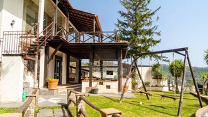 A building with a wooden staircase, a covered outdoor area, and a swing set. - Villa "Nel Verde" dell'Etna with Sea View, Pool, Wi-Fi, Terrace and Garden (piedimonte etneo)