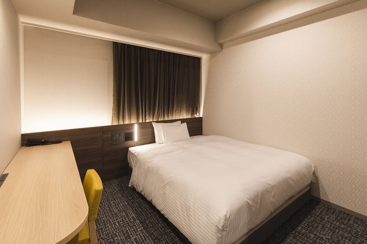 Una habitación de hotel con cama, escritorio y silla.