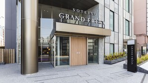 The exterior of a hotel named "Sotetsu Grand Festa" with a modern design, featuring a prominent entrance, large windows, and a metallic pillar. - SOTETSU GRAND FRESA TAKADANOBABA (Tokyo)