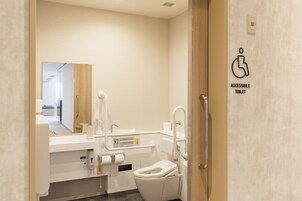 Une salle de bain moderne et accessible, équipée de toilettes, d’un lavabo et d’une barre d’appui.