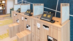 A self-check-in kiosk area with multiple self-check-in stations, a reception desk, and a patterned wall in the background. - SOTETSU GRAND FRESA TAKADANOBABA (Tokyo)