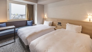 A hotel room with two beds, a window with a view, a small table, and a wall-mounted lamp. - SOTETSU GRAND FRESA TAKADANOBABA (Tokyo)