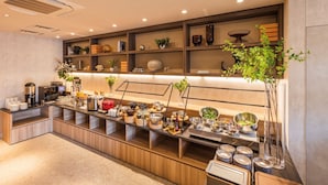A modern kitchen with a long counter, equipped with various appliances and utensils, and shelves above holding decorative items and plants. - SOTETSU GRAND FRESA TAKADANOBABA (Tokyo)