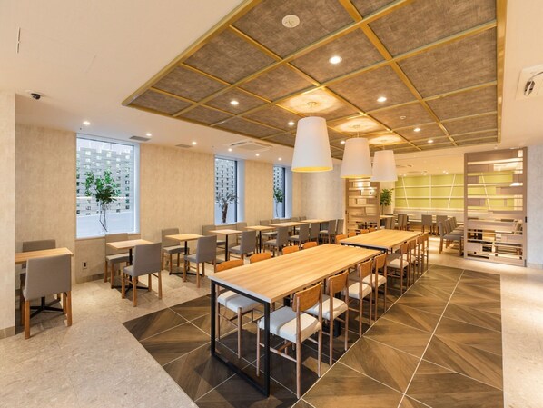 A modern dining area with long tables and chairs, a high ceiling with exposed beams, and large windows providing natural light. - SOTETSU GRAND FRESA TAKADANOBABA (Tokyo)