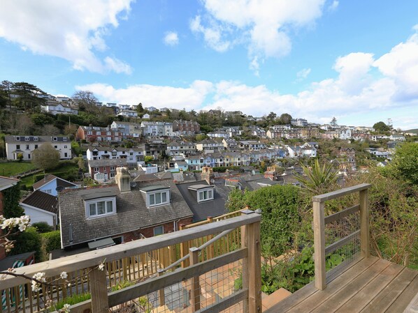 A residential area with houses on a hillside, a wooden deck, and a metal fence.