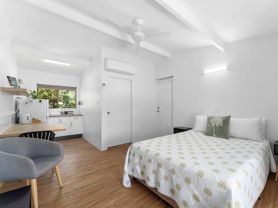 Un dormitorio moderno con cama, mesitas de noche, un escritorio y una silla.