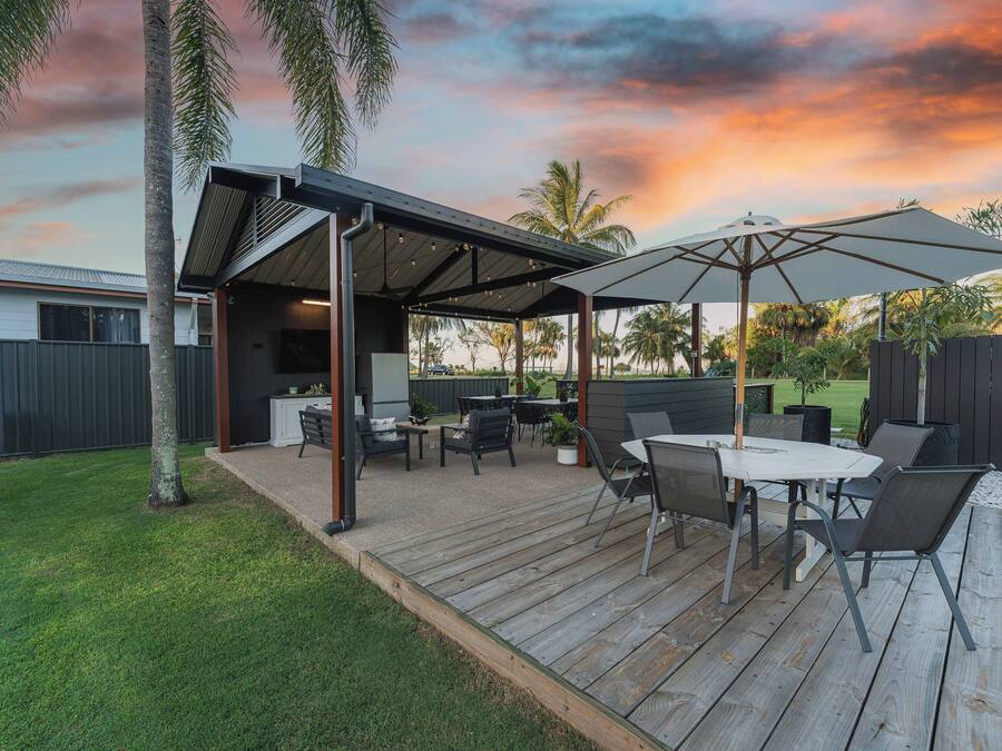 Une terrasse extérieure dotée d’un espace salon abrité, d’une table et de chaises.
