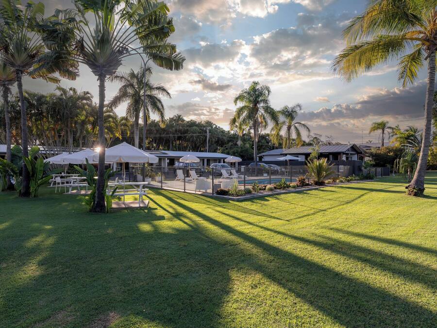 A resort with outdoor seating, palm trees, and a pool area.