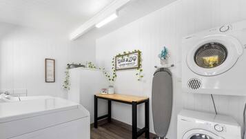 Une buanderie équipée d’un lave-linge, d’un sèche-linge et d’une table sur laquelle est posée une pancarte.