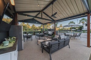 An outdoor patio with a grill, seating, and a view of palm trees. - Kinka Palms Motel (Kinka Beach)