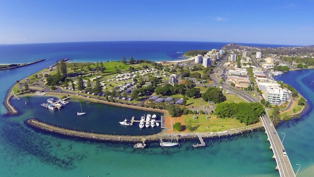 Vue aérienne d’une zone côtière comprenant un port de plaisance, des immeubles résidentiels et un pont.