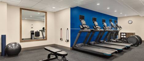 A gym with treadmills, a bench, exercise balls, and a mirror.