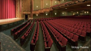 Un théâtre avec des sièges rouges, une scène et des éléments architecturaux richement décorés.
