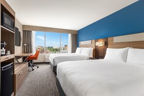 Een hotelkamer met twee bedden, een bureau, een stoel en een televisie.
