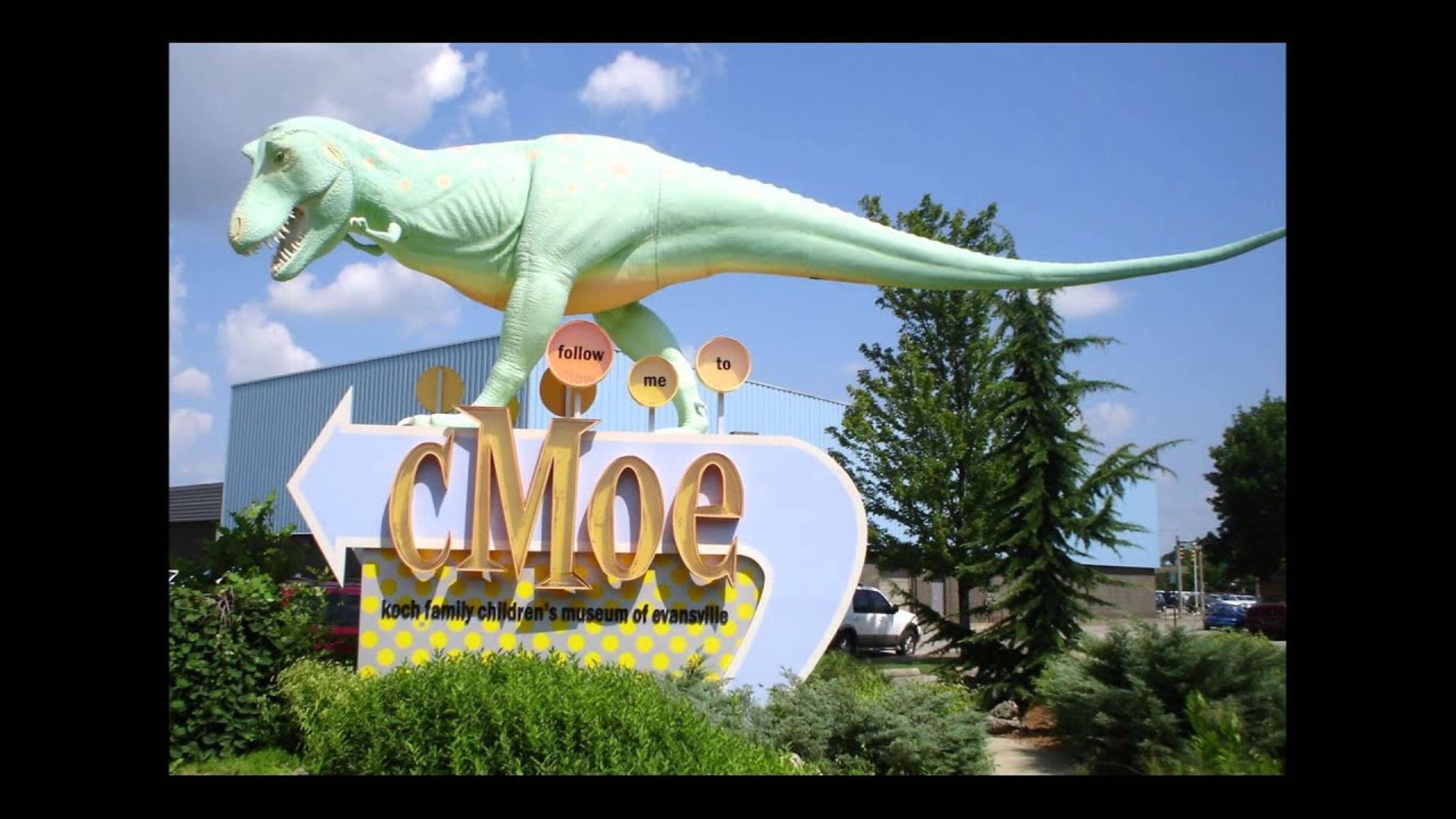 A dinosaur statue on a sign for the Koch Family Children's Museum of Evansville.