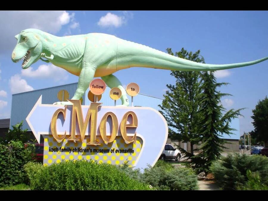 A dinosaur statue on a sign for the Koch Family Children's Museum of Evansville.