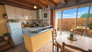 A kitchen with a central island, wooden cabinets, and a dining area with a table and chairs.
