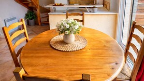 A wooden dining table with chairs, a vase of flowers, and a woven placemat.