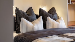 A bed with a dark headboard and multiple pillows, including a unique textured pillow and a striped one. - 25 Walkers Lane - Luxurious living with breath taking views (Bright)