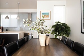 Un comedor moderno con una mesa de madera, sillas de cuero negro y dos plantas grandes en macetas.