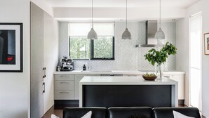 A modern kitchen with a large window, pendant lights, and a central island.