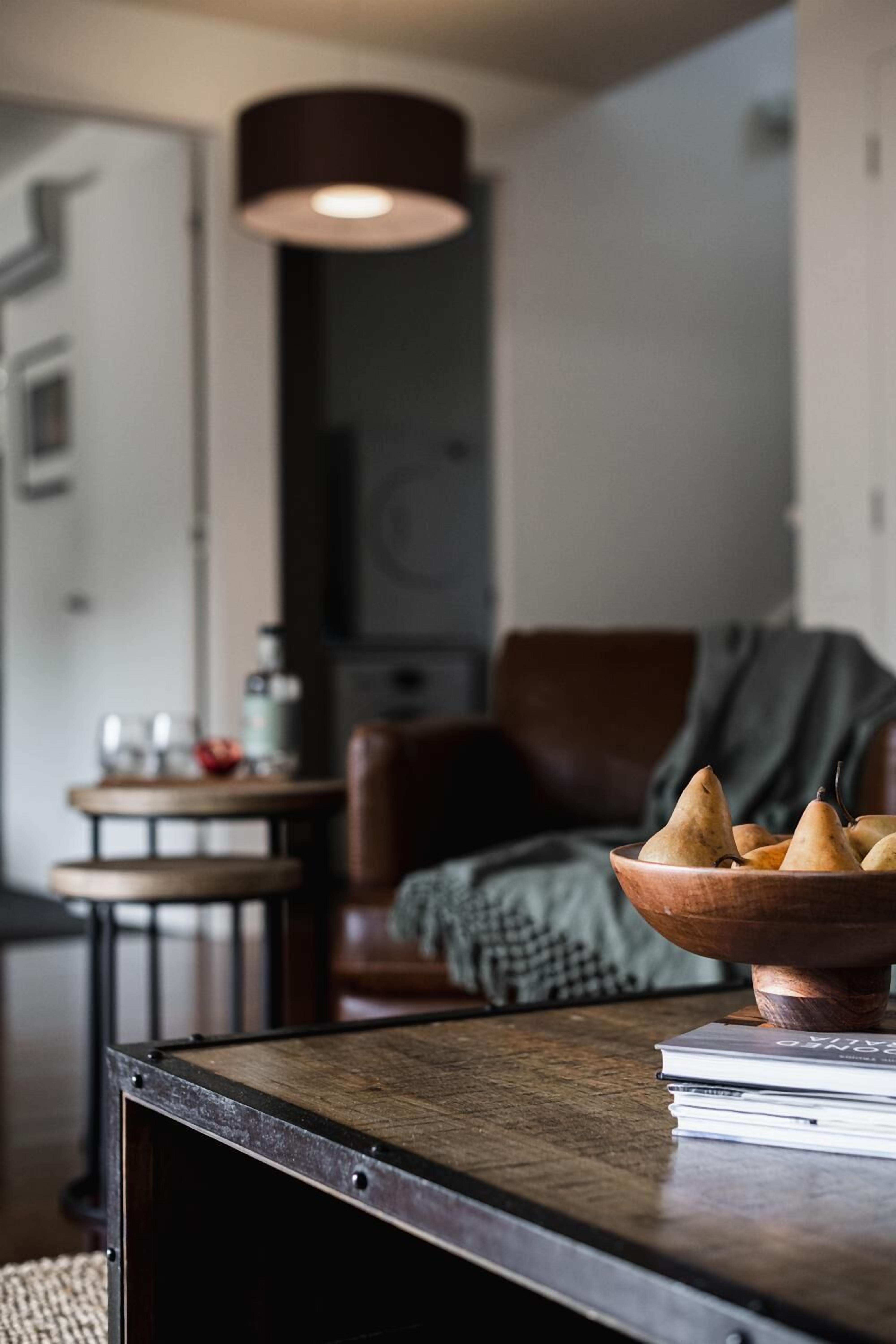 Un salon chaleureux avec une table basse en bois, un panier de poires et une bibliothèque.