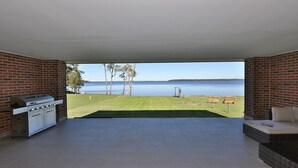 Ein offener Wohnbereich mit Küche, Blick auf einen See und Sitzgelegenheit im Freien.