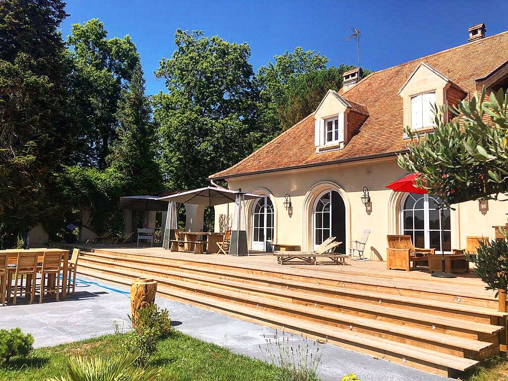 A building with a patio area, outdoor seating, and a staircase leading to the entrance.
