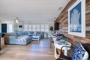 Relax in this stylish living room with a large sectional sofa, coffee table, and dining area.