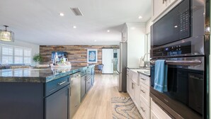 Una cocina moderna con una isla grande, electrodomésticos de acero inoxidable y una pared de acento de madera.
