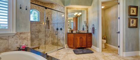 A spacious bathroom with a large bathtub, a walk-in shower, and a vanity with a mirror and sink.