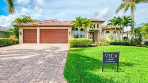 A two-story house with a red-tiled roof, a garage, and a well-maintained lawn. - VRCC Villa Belle Mer (Cape Coral)